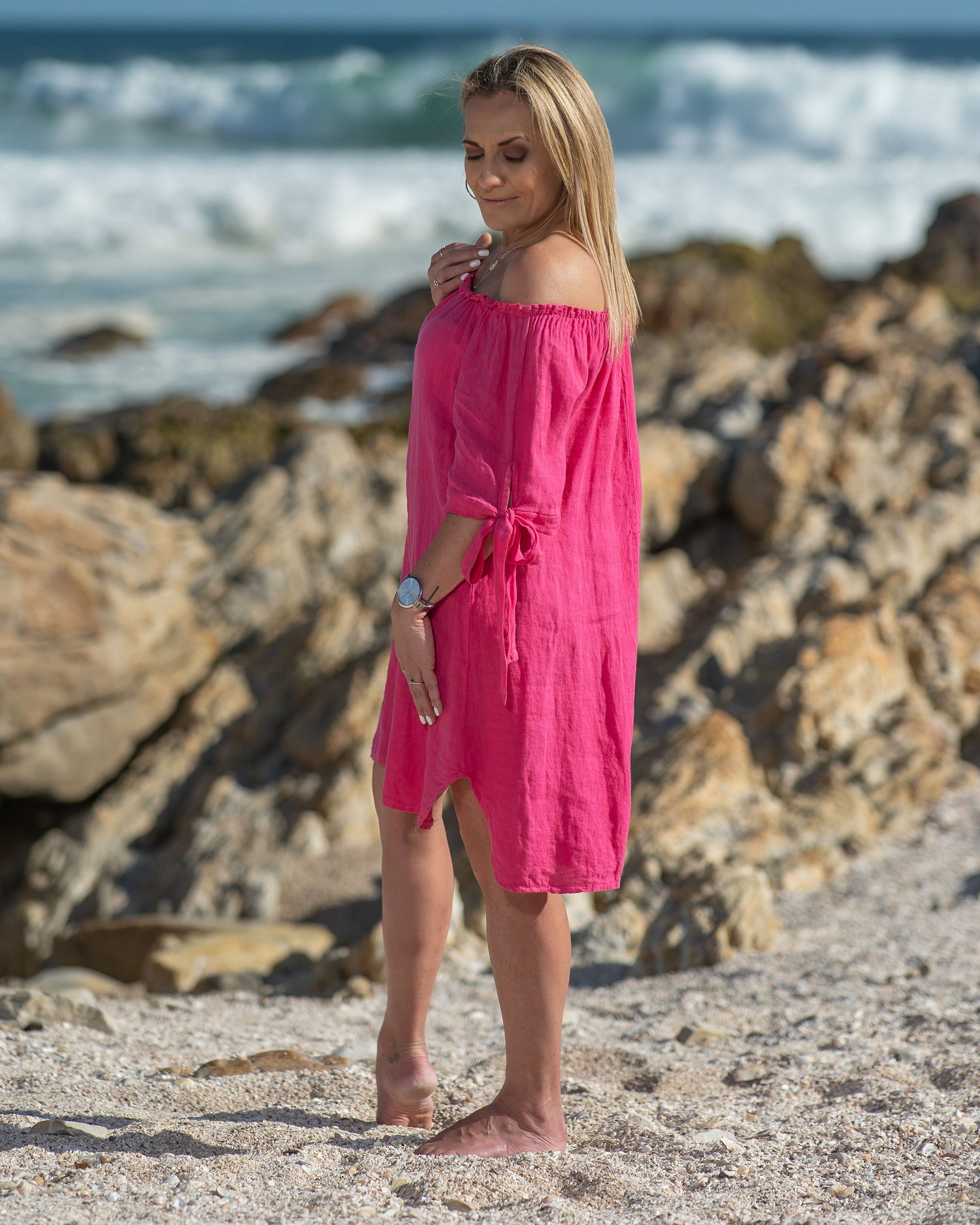 The elasticated neckline offers a flattering and secure fit, allowing you to showcase your shoulders and collarbone with effortless grace. What sets this dress apart are the charming drawstrings on the arms. The mini length adds a playful vibe to the dress, making it ideal for casual outings, beach strolls, or weekend brunches