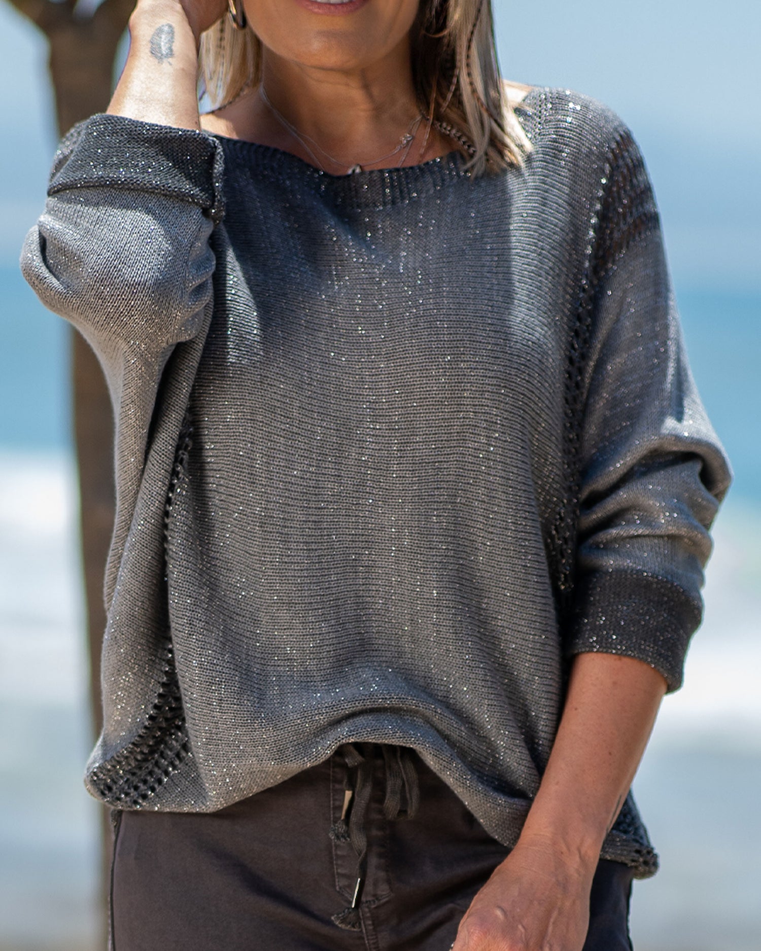 This knit features a playful infusion of glitter threads throughout, creating a shimmering effect. Batwing cut ensure ultimate comfort with a flattering overall fit. Ribbed side panels that not only enhance the overall fit but also provide a subtle texture contrast